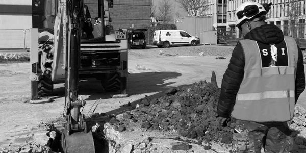 Construction worker operating excavator at urban site.