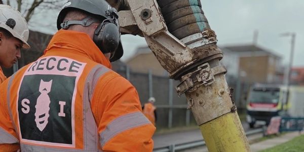 Workers in safety gear operating heavy machinery at a construction site.