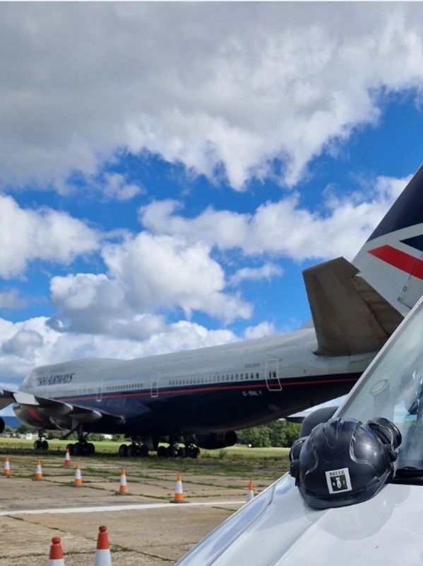 Vintage British Airways airplane on runway with pilot helmet in foreground.
