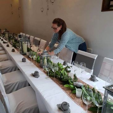 Florist setting up an elegant table display with greenery and lanterns for a Daventry wedding