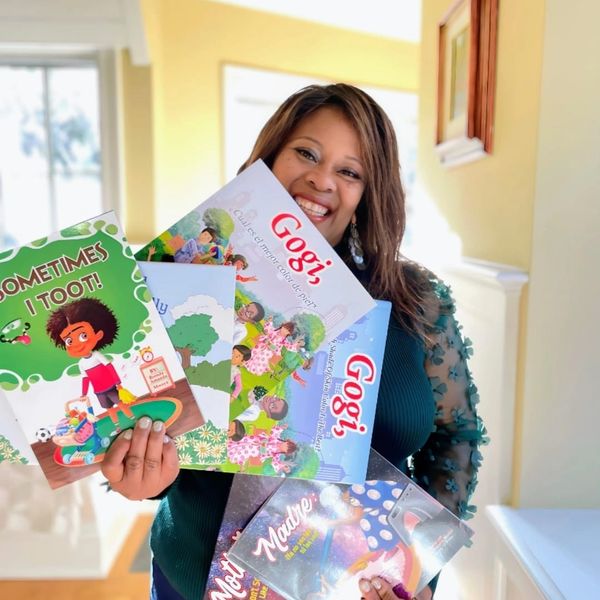 A woman holding Gogi story books