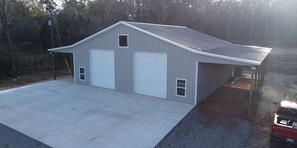 Modern metal building with two large garage doors and a covered side area.