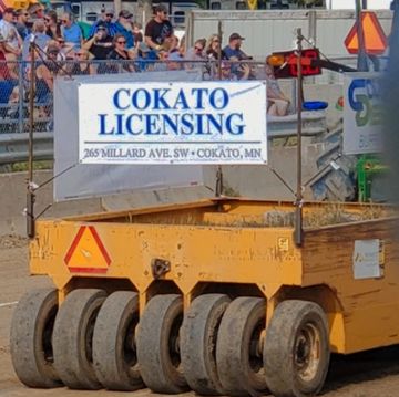 Vehicle with Cokato Licensing sign at an outdoor event.