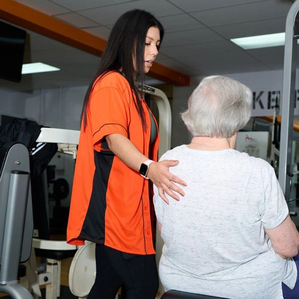 personal trainer Training her senior client in a gym Working on strength training for bone strength