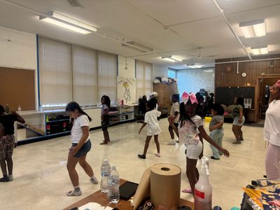 Children practicing dance moves in a classroom with an instructor.