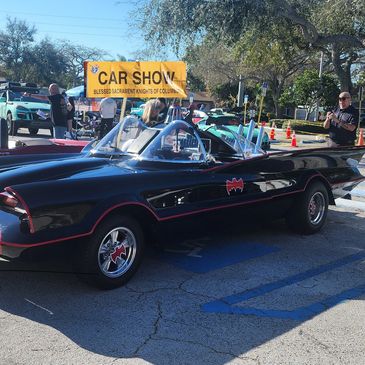Classic black Batmobile car at a car show event outdoors.