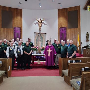 Group photo inside a church altar with a priest and parishioners.