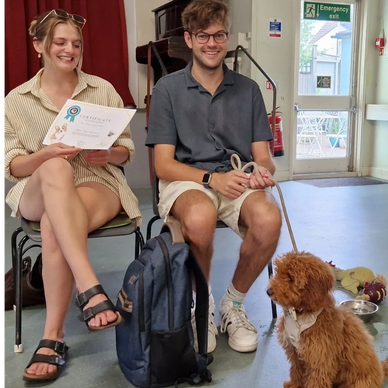 Happy young couple with their well behaved puppy at a puppy training class in Teddington