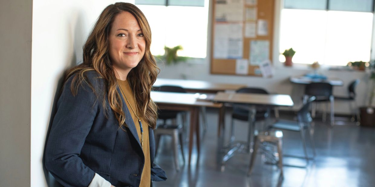 Woman smiling confidently in an office or classroom setting.