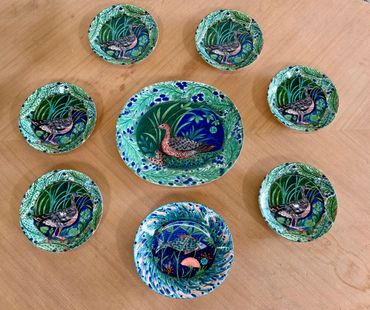 Decorative ceramic plates with colorful bird designs arranged on a wooden surface.