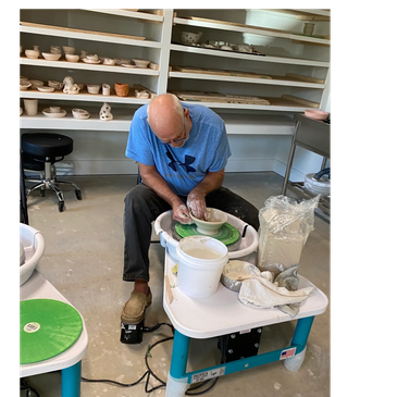 Man shaping clay on a pottery wheel in a studio.
