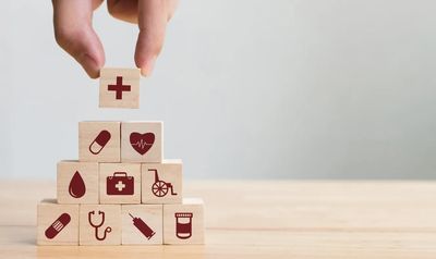 Hand Holding Wooden Blocks With Medical Icons on Them