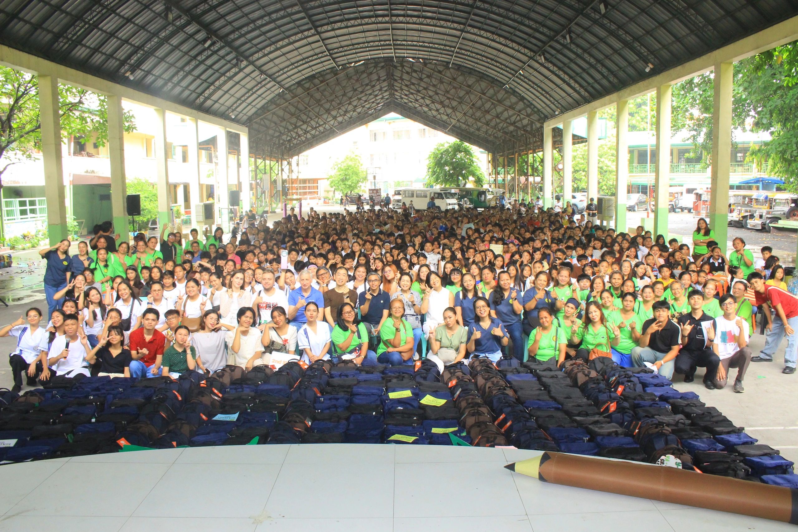Large group photo under a covered pavilion with backpacks in front.