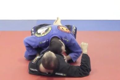 Two martial artists practicing Brazilian Jiu-Jitsu on mats.
