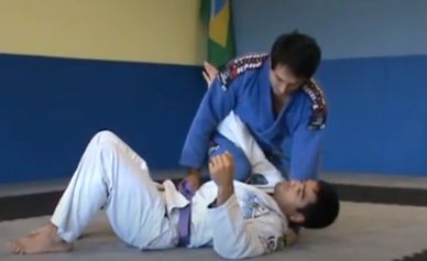 Two men practicing Brazilian Jiu-Jitsu on mats in a gym.