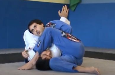 Two individuals practicing Brazilian Jiu-Jitsu grappling techniques indoors.