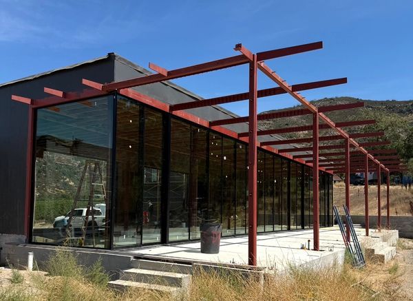 Modern glass building under construction in a rural area.