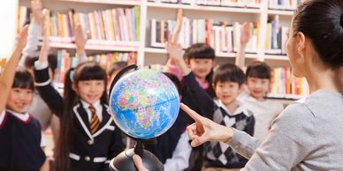 Teacher holding a globe, engaging students in a classroom – WorldConnect Education, global learning