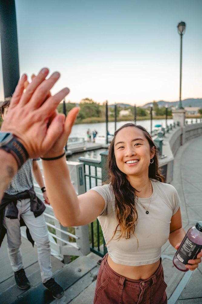 Group of people kayaking under a concrete bridge in a scenic river.