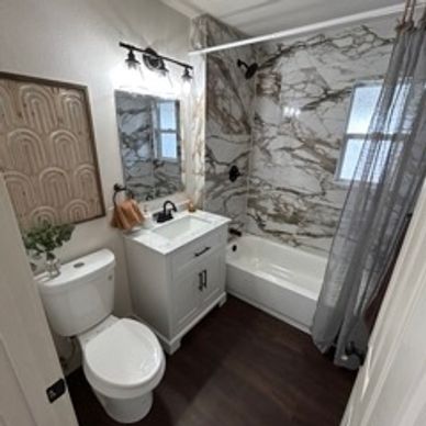 Bathroom remodel with new toilet, mirror, bathtub, tile, flooring, vanity and lighting. 
