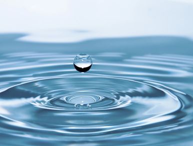 Gota de agua suspendida sobre una superficie acuática.