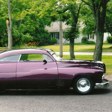 Classic purple vintage car parked on a suburban street.