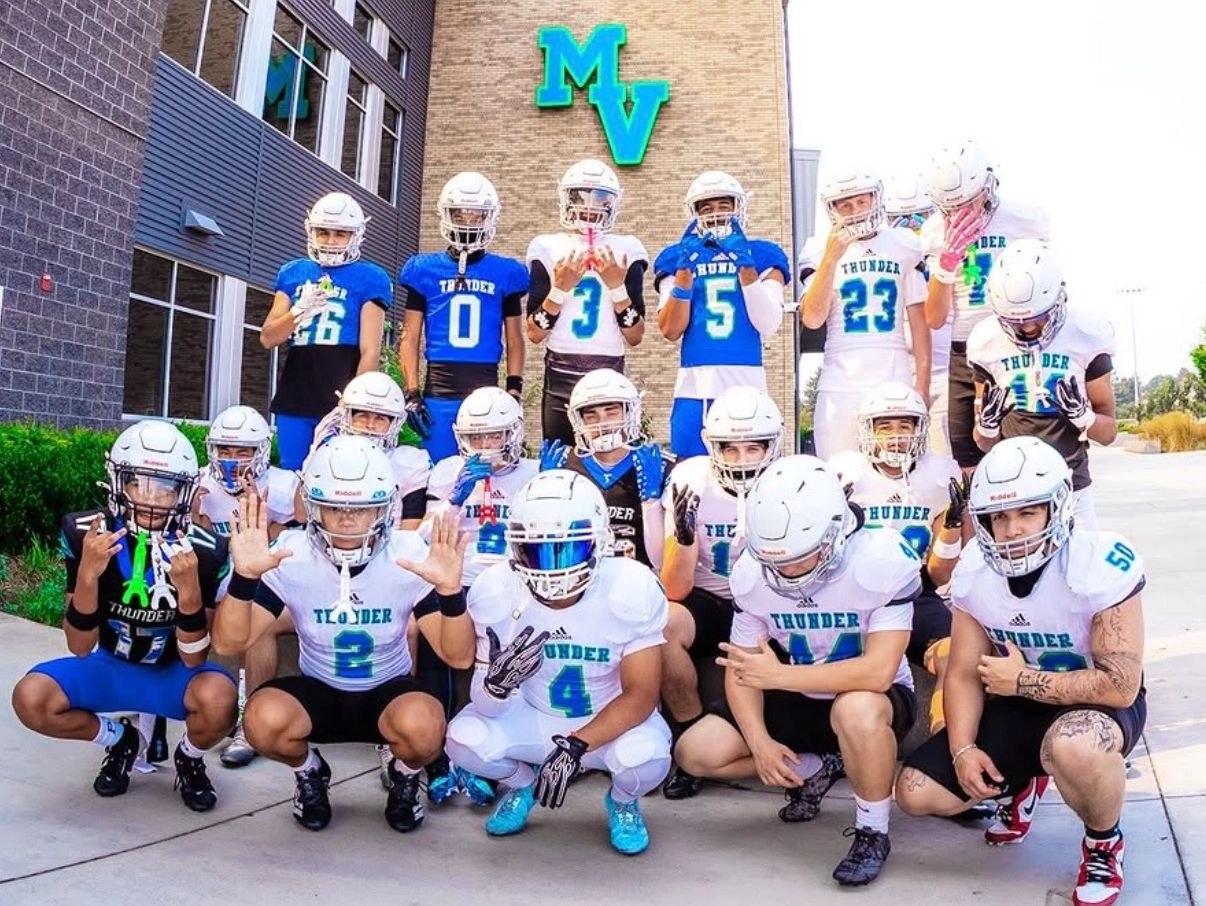 Youth football team posing together outside a building.