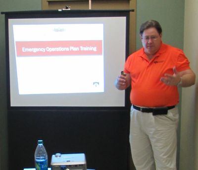 Man in orange shirt presenting emergency operations plan training.
