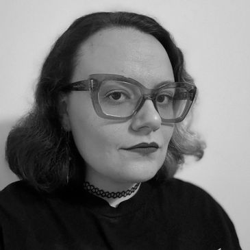 Person wearing large purple glasses and dark lipstick.