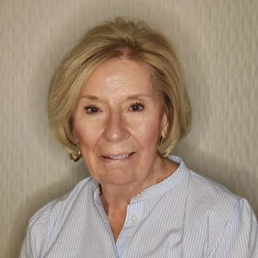 Portrait of a smiling elderly woman with short blonde hair.