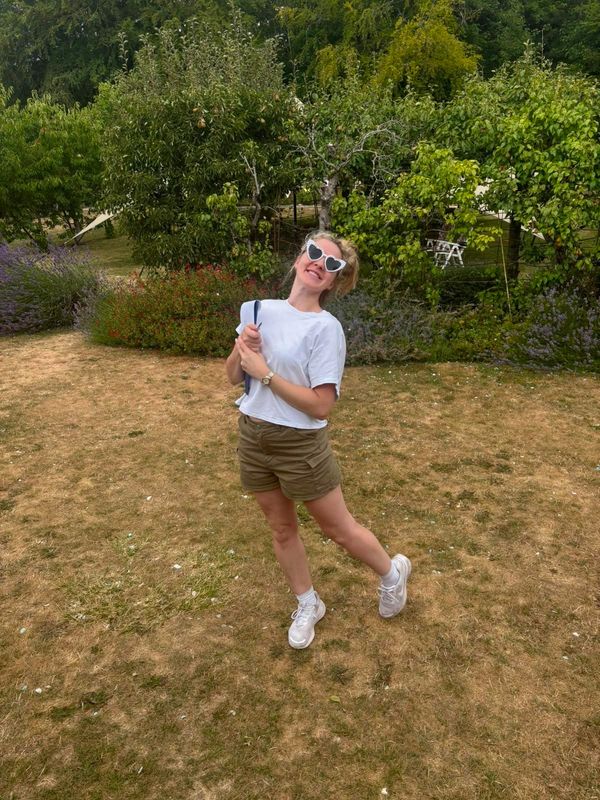 Woman posing happily outdoors in heart-shaped sunglasses.