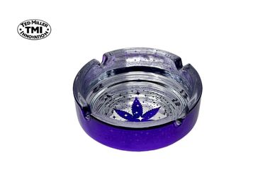 Purple glass ashtray with a cannabis leaf design at the center.