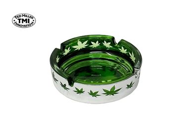 Green glass ashtray with cannabis leaf designs around the edges.
