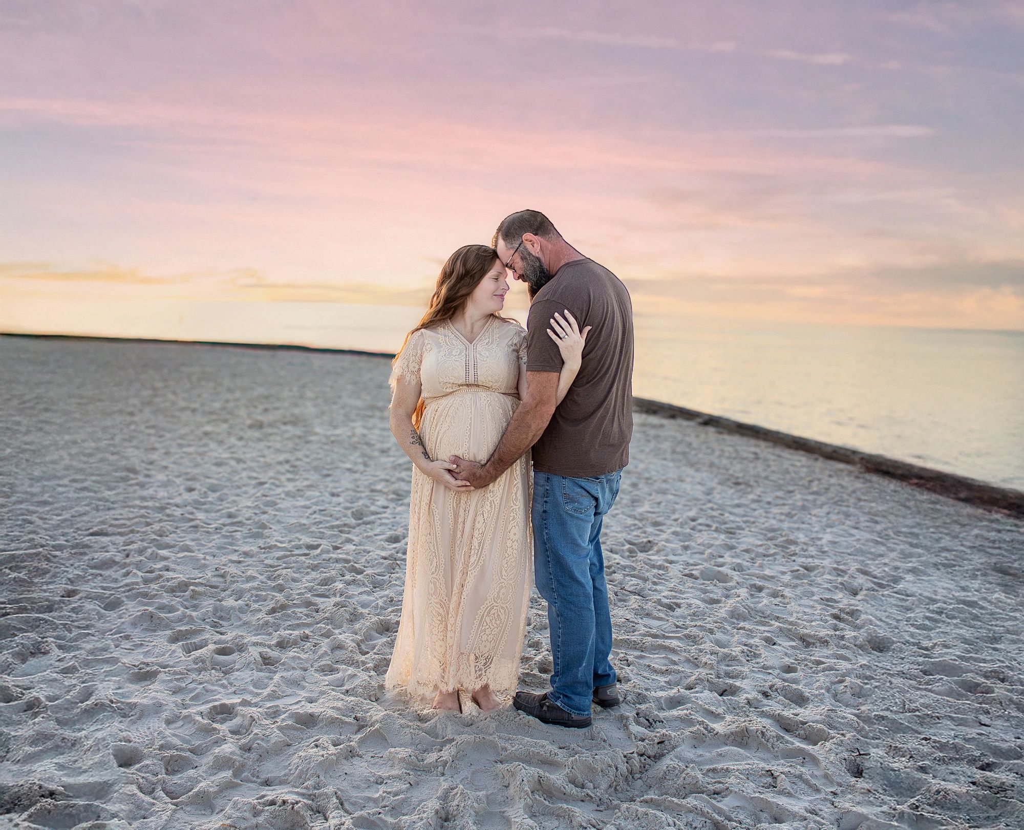 Couple embracing on beach at sunset.