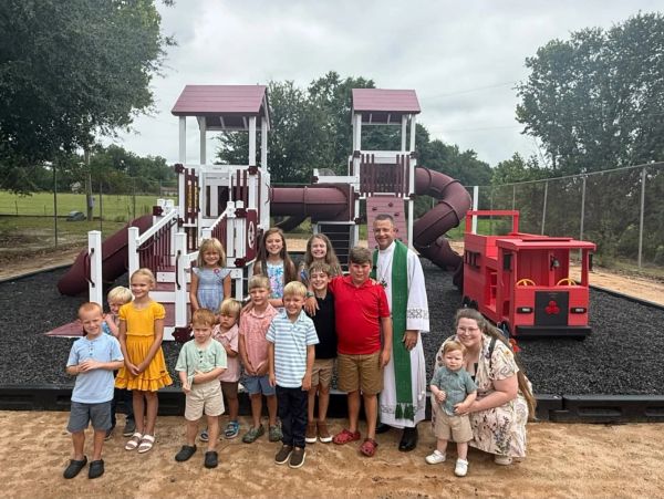 Group of children and two adults at a playground.