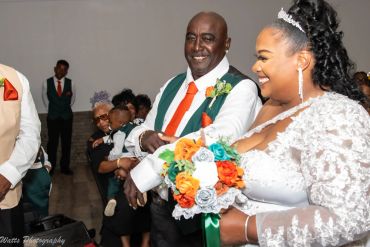 Smiling bride and man holding a child at a wedding.