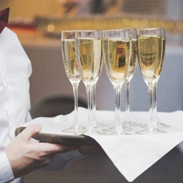 Server, waitstaff, event staff serving champagne on a platter, tray to pass out to guests