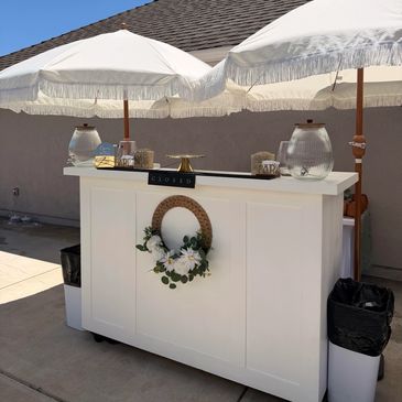 White, beautiful wooden bar set up before an event with decor related its theme and colors