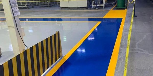 Blue and yellow painted floor markings in an industrial setting.