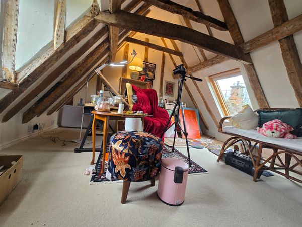 Cozy attic workspace with wooden beams and eclectic furniture.