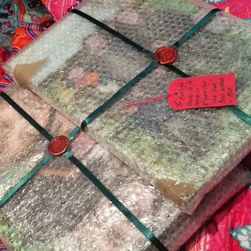 Two bubble-wrapped, ribbon-tied packages with red wax seals and a red tag.