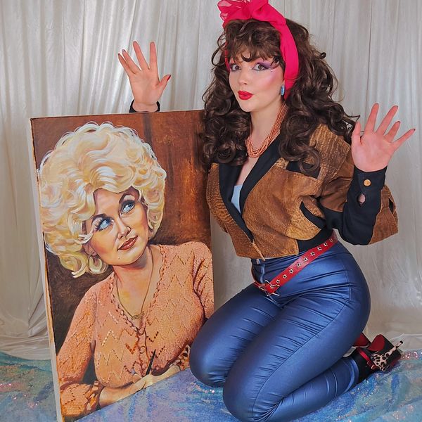 Woman posing with a retro painting, wearing vibrant 80s fashion and makeup.