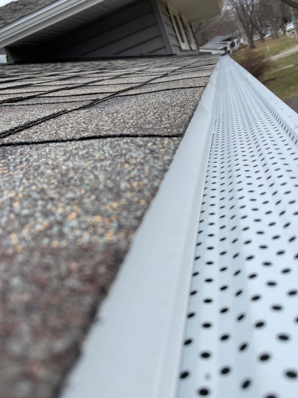 Close-up of a roof gutter and shingle edges on a house.