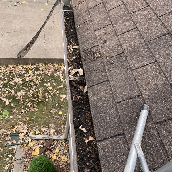 A clogged gutter filled with leaves and debris along a roof edge.