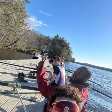 Group of friends sitting on a dock by the water on a sunny day.
