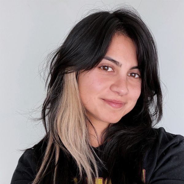 Young woman with black hair and blonde streaks smiling.