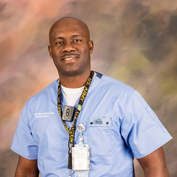 A male Registered Nurse standing with his nursing scrub and smiling.