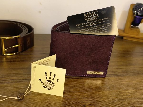 Elegant maroon leather wallet with authenticity certificate on a wooden surface.