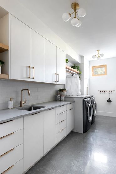 white laundry room cabinets slab gold handles concrete floor oak shelves