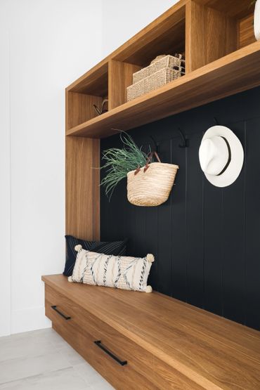 white oak custom bench seat entry millwork storage cabinets open shelves black slat wall with hooks